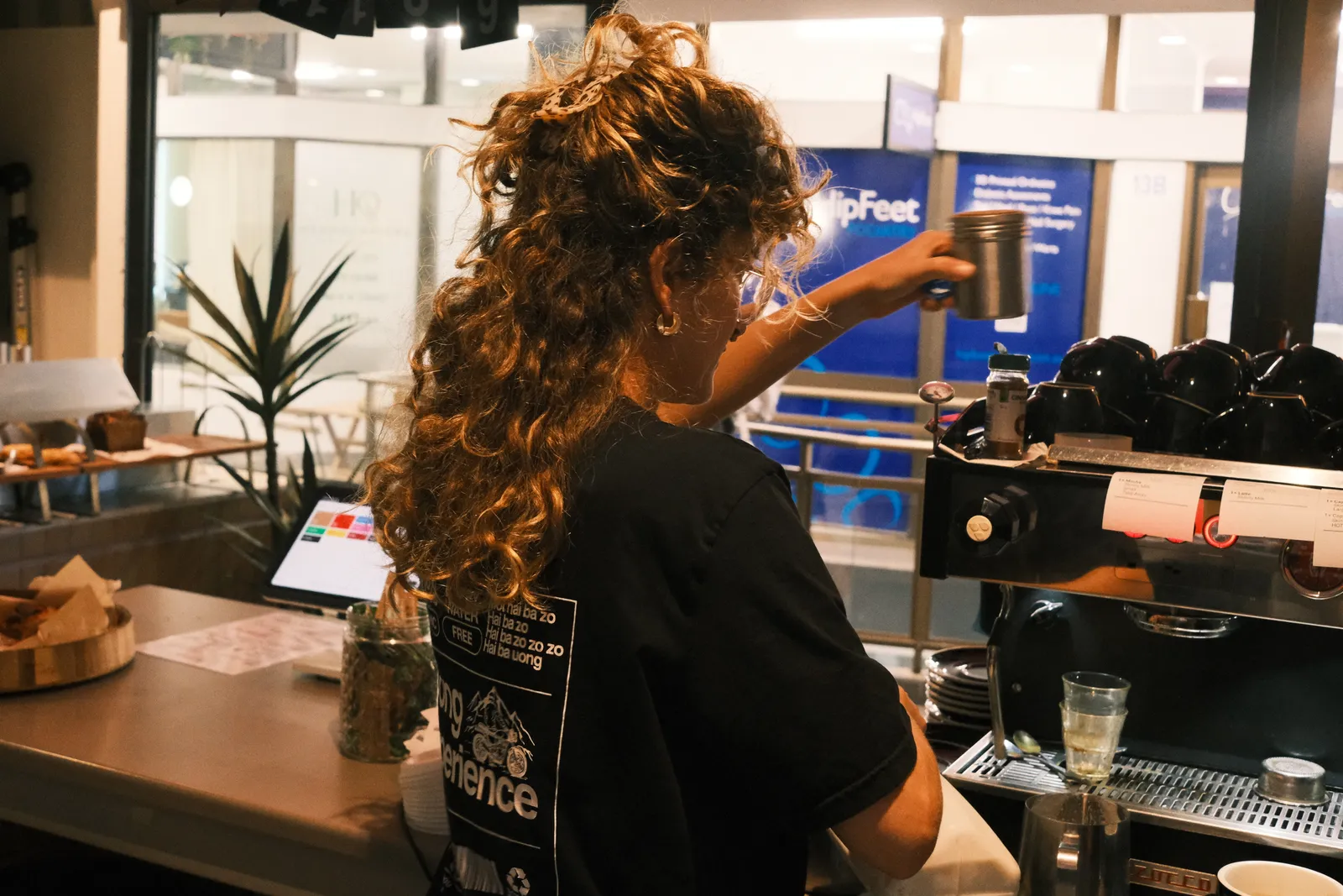 A barista at the coffee machine behind the counter.