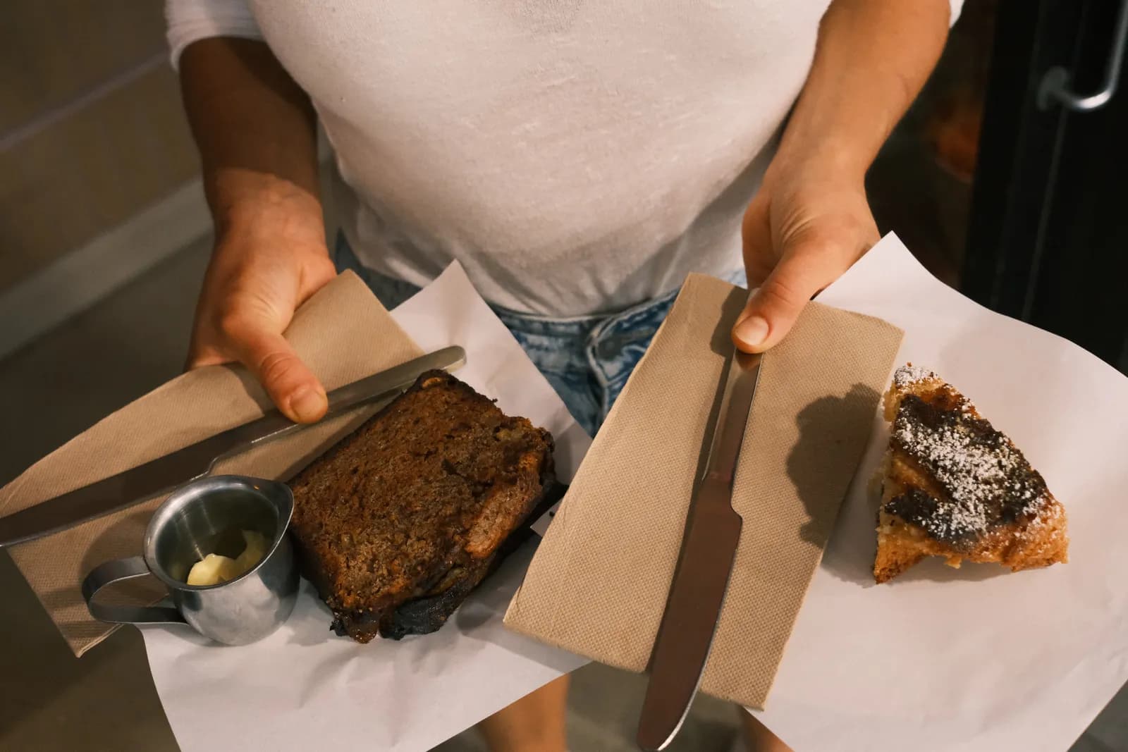 Two slices of cake served on paper over the counter.